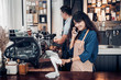 © weedezign - Asia Barista waiter use tablet take order from customer in coffee shop,cafe owner writing drink order at counter bar,Food and drink business concept,Service mind concept.restaurant worker.