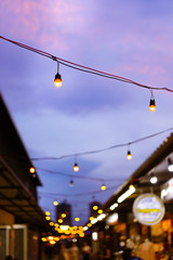 Decorative outdoor string lights hanging on electricity post in the garden at night time with blur people. Christmas,festival, holiday and wedding concepts.