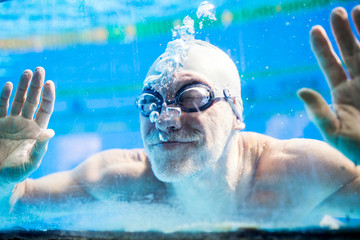 Wall Mural - Senior man swimming in an indoor swimming pool.