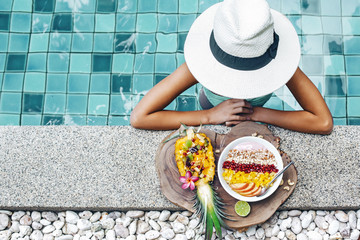 Girl eating exotic fruits in the pool