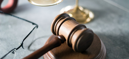 Poster - Law and Justice concept. Mallet of the judge, glasses, scales of justice. Gray stone background, reflections on the floor, place for typography. Courtroom theme.