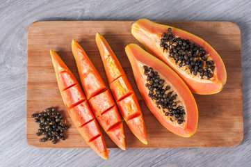 Papaya fruit cut in slices on wooden background