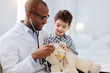 © Viacheslav Yakobchuk - Doctor for toy. Merry glad male doctor posing with boy on light background while examining plush bear and talking