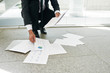 © DragonImages - Unrecognizable businessman picking up documents fallen on floor