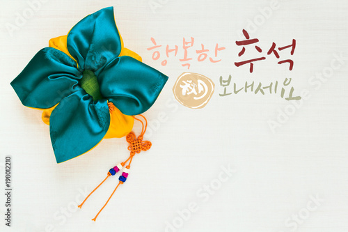 Fotografía 'Happy Chuseok & Hangawi, Translation of Korean Text : Happy Korean Thanksgiving Day' calligraphy and Korean traditional bag & knot background of white ramie fabric
