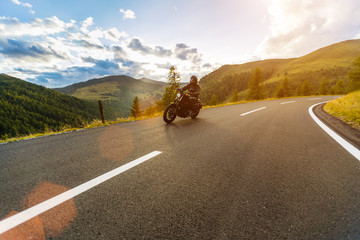 Motorcycle driver riding in Alpine highway, Nockalmstrasse, Austria, Europe.