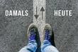 Vor einer wichtigen Entscheidung stehen über damals und heute in der Zukunft symbolisiert durch Füße auf zwei unterschiedlichen Farben auf Straße