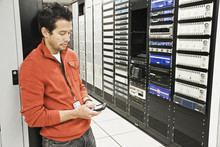 Caucasian Male Technician On A Cell Phone In A Large Computer Server Room.
