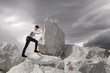 © Sondem - Business concept, Young businessman pushing large stone uphill with copy space