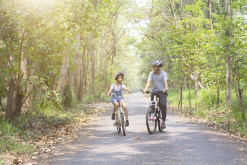 Wall Mural - Happy father and daughter cycling in the park, togetherness relaxation concept