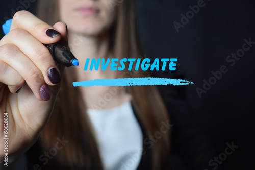 Foto The businessman writes a blue marker inscription:INVESTIGATE