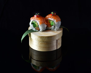 Two pieces of sushi on a round box isolated on black