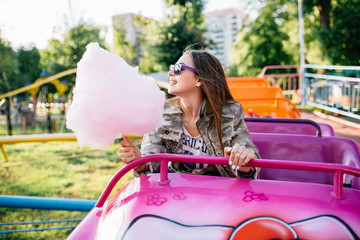 Wall Mural - Joyful girl eating a cotton candy, while riding a roller coaster