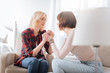 © zinkevych - Mutual support. Nice pleasant lesbian couple sitting on the sofa and holding each others hands while expressing their support