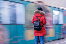 A Girl In A Red Jacket With A Backpack Stands With Her Back On The Moscow Subway Platform Against The Background Of The Departing Train