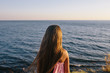 © skvalval - girl in a pink dress standing by the sea. rear view