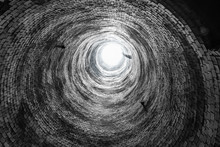 Abstract Image Looking Up An Abandoned Brick Smoke Stack. Round Circle Repeating Pattern Of Old Bricks, And Light At The End