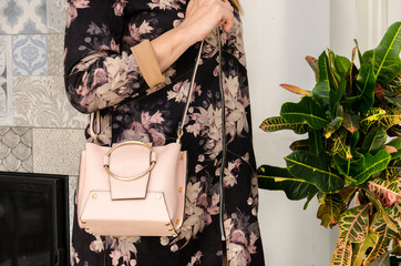 woman is holding a small stylish bag (clutch) of soft beige color with an iron metal ring