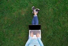 Top View Of Woman Sitting In Park On The Green Grass With Laptop