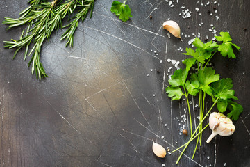 Wall Mural - Food background. Parsley and rosemary on a dark stone table. Copy space, top view flat lay background.