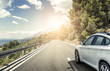 canvas print picture - A white car rushing along a high-speed highway in the sun.