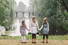 Three Little Girls Walk In Park With Lake View