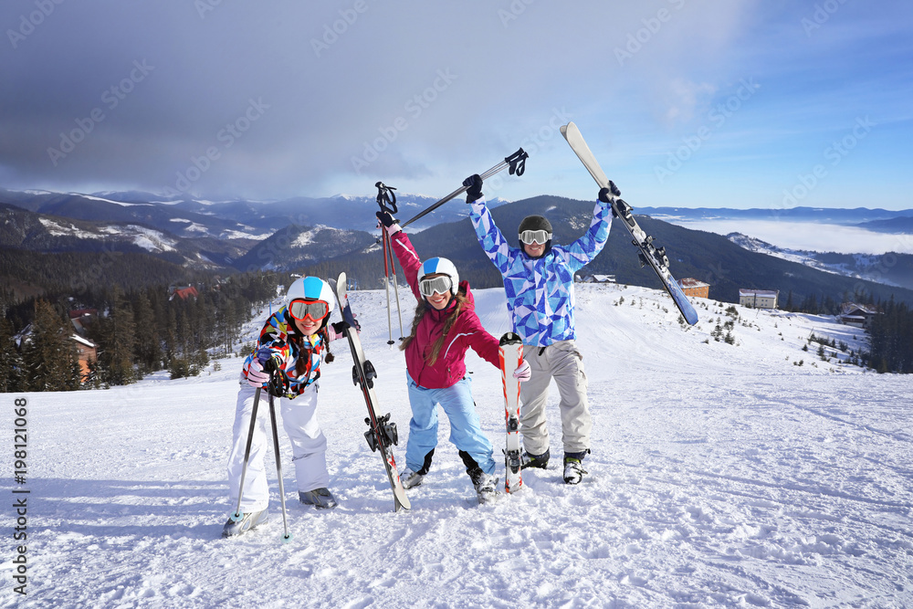 Happy friends on ski piste at snowy resort. Winter vacation