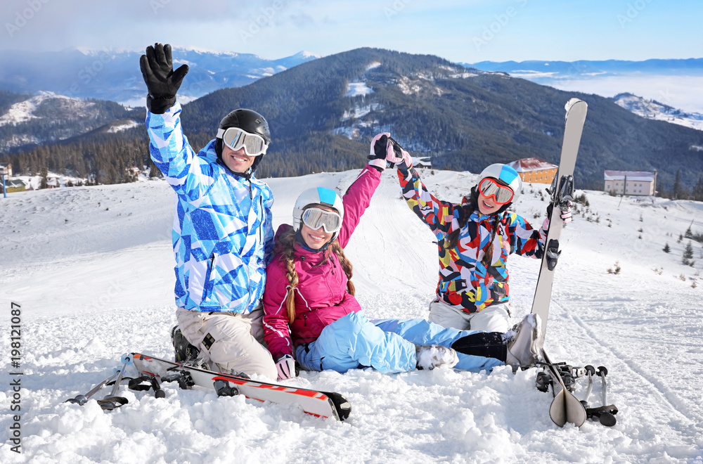 Happy friends on ski piste at snowy resort. Winter vacation