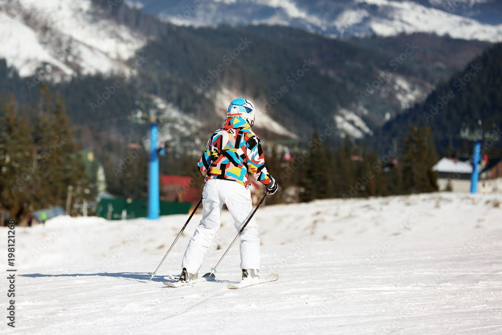Woman skiing on piste at snowy resort. Winter vacation
