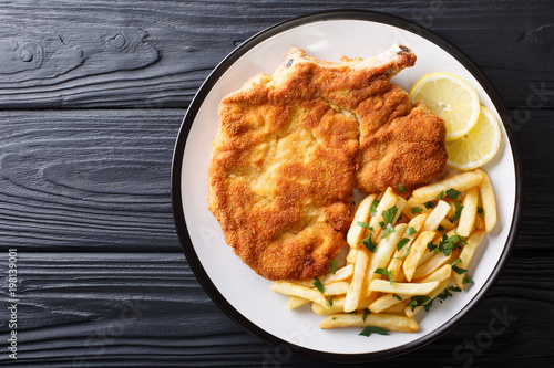 Fotomural Traditional Italian veal Milanese with lemon and French fries close-up