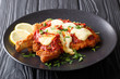 © FomaA - Delicious veal cutlet with mozzarella cheese, lemon and tomato sauce (milanesa napolitana) close-up. horizontal