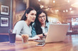 © Viacheslav Yakobchuk - This is interesting. Positive nice female friends sitting together and looking at the laptop screen while meeting at the bar