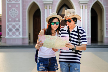 Couple of traveler using local map together for go to destination in the city. tourist couple have a good time on vacation background is the church. Happy family go to travel on holiday.