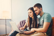 © Мария Кокулина - Young couple sitting at home and  using laptop, surf the Internet.