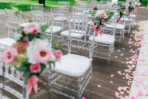 Outdoor Wedding Ceremony With White Plastic Chairs Decorated With