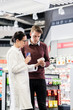 © Kzenon - Experienced female pharmacist checking the indications and contraindications of a new medicine next to a young male customer in a modern pharmacy