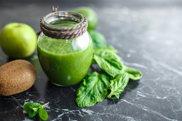 Blended green smoothie with ingredients on table