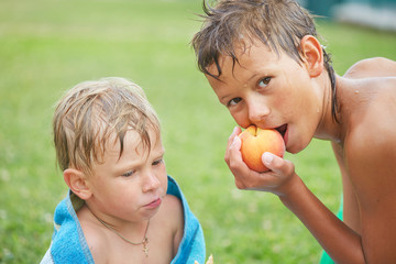 Wall Mural - A child with a wet head in a towel after a pool eats a cookie.