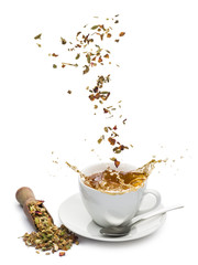 Wall Mural - cup of tea with tea mixture falling and splashing on white background