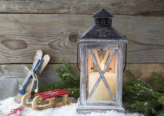 christmas background: lantern with a tree with a candle and skis, sledges