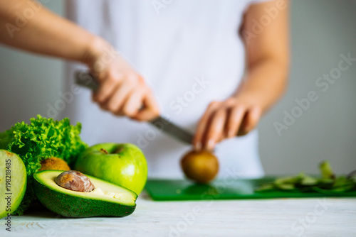 Zdjęcie XXL zielone owoce z przodu. kobieta cięcia owoców na tle. koncepcja zdrowej żywności