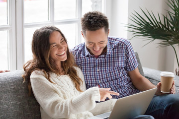 Sticker - Young happy couple watching funny video online, cheerful family having fun with laptop sitting on sofa at home, boyfriend and girlfriend friends laughing out loud at internet hilarious joke together