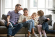 © fizkes - Cheerful young family with kids laughing watching funny video on smartphone sitting on couch together, parents with children enjoying playing games or entertaining using mobile apps on phone at home