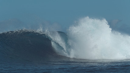 Wall Mural - Countless turquoise water drops fly around powerful ocean wave approaching beach