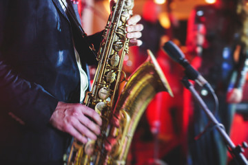 Concert view of a saxophone player with vocalist and musical jazz band in the background