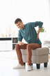 © New Africa - Young man suffering from back pain at home