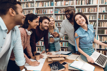 Wall Mural - Group of ethnic multicultural students talking and laughing in library.