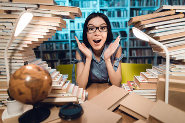 Wall Mural - Ethnic asian girl surrounded by books in library at night. Student is looking amazed.