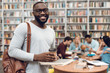 © freeograph - Group of ethnic multicultural students in library. Black guy with notes and coffee.