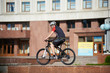 © anatoliy_gleb - Guy bicyclist in professional cycling clothing and helmet training on street edge, ready to jump. Man exercising before contest, improving riding skills. Concept of motivation, achievement, success